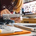 Una mujer usando diferentes herramientas digitales en una mesa de escritorio.