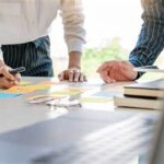 Dos personas elaborando un proyecto sobre una mesa de oficina.